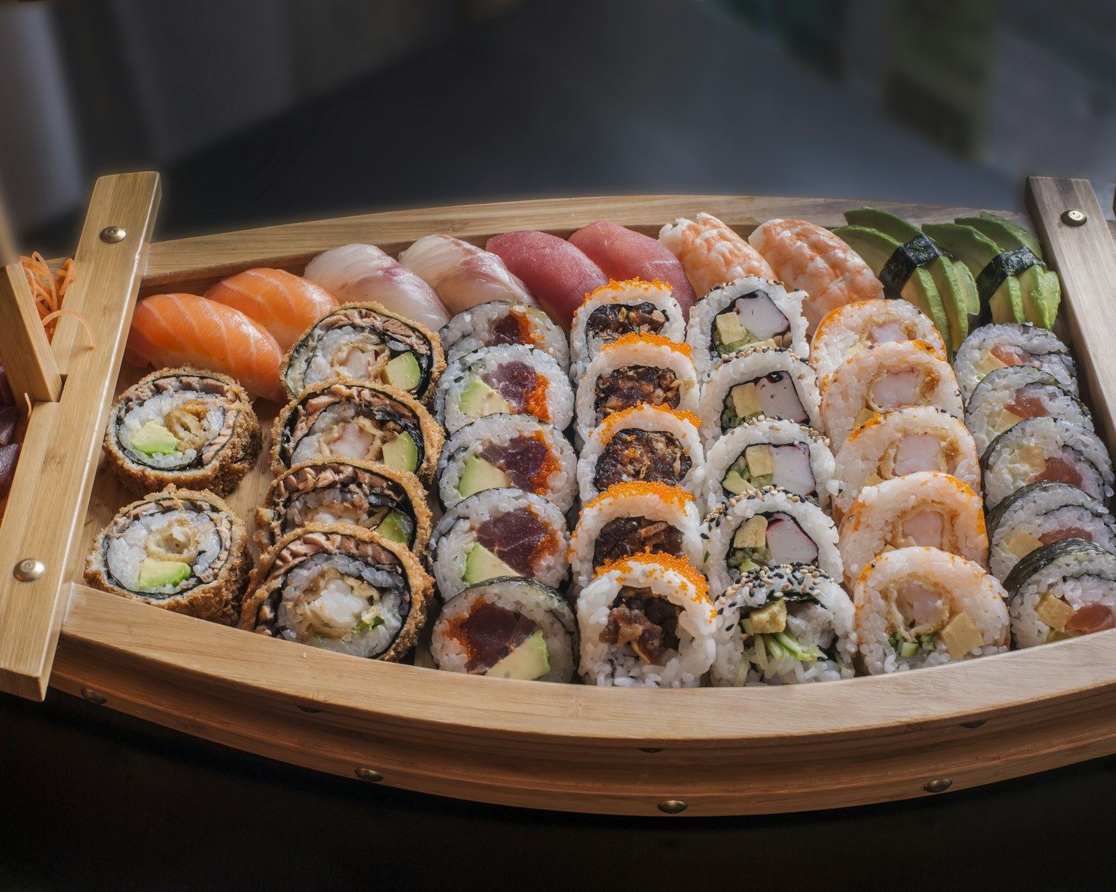 Barca di legno piena di uramaki, nigiri e maki assortiti